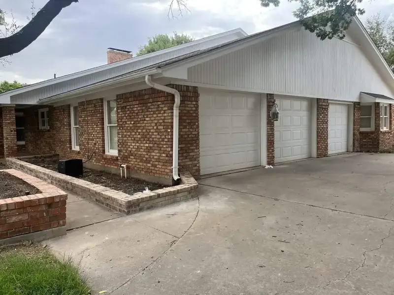 Exterior before: red brick, white garage doors