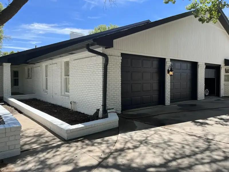 Exterior after: brick painted white, black garage doors